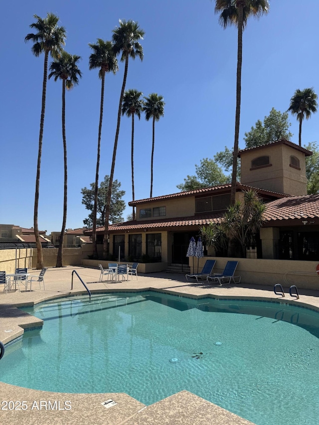 pool with a patio area and fence