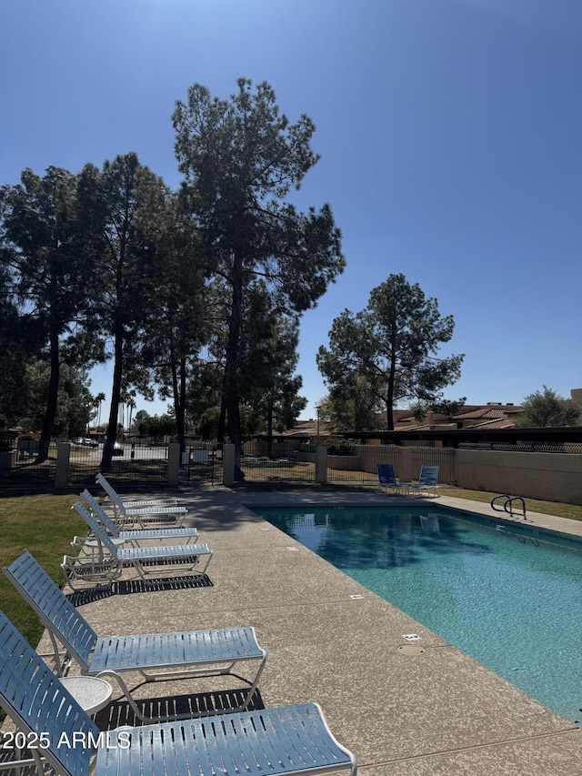 community pool with a patio and fence