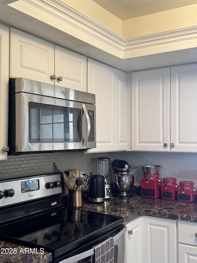 kitchen featuring dark stone counters, appliances with stainless steel finishes, and white cabinets