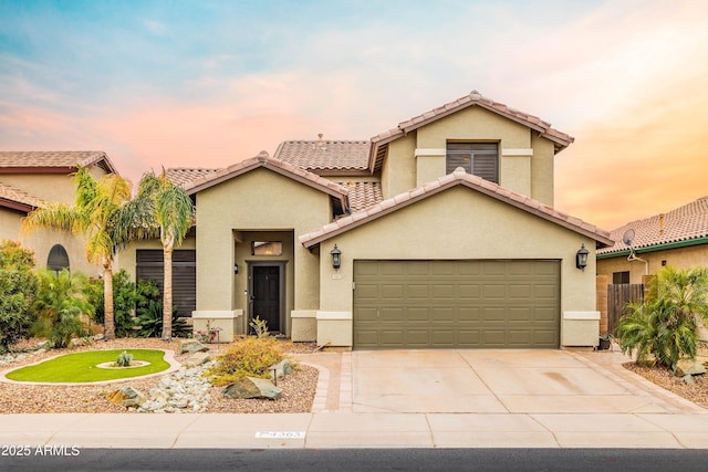 view of front facade with an attached garage, a tile roof, concrete driveway, and stucco siding