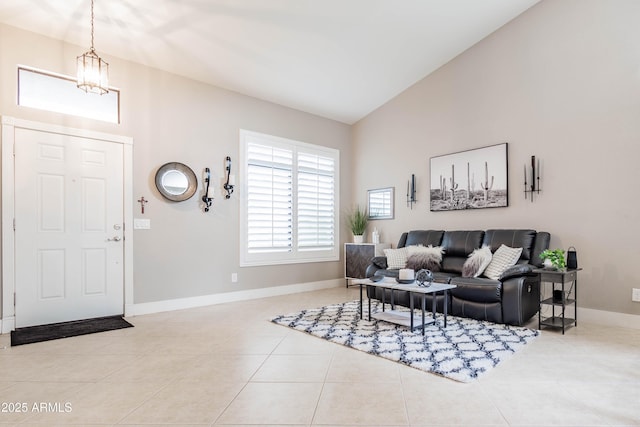 living area featuring lofted ceiling, baseboards, a chandelier, and light tile patterned flooring