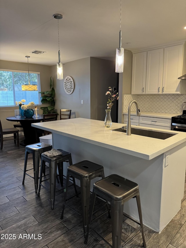 7635 E Verde Ln, Scottsdale, AZ 85251 - kitchen with a kitchen bar, a sink, white cabinets, and dark wood-type flooring
