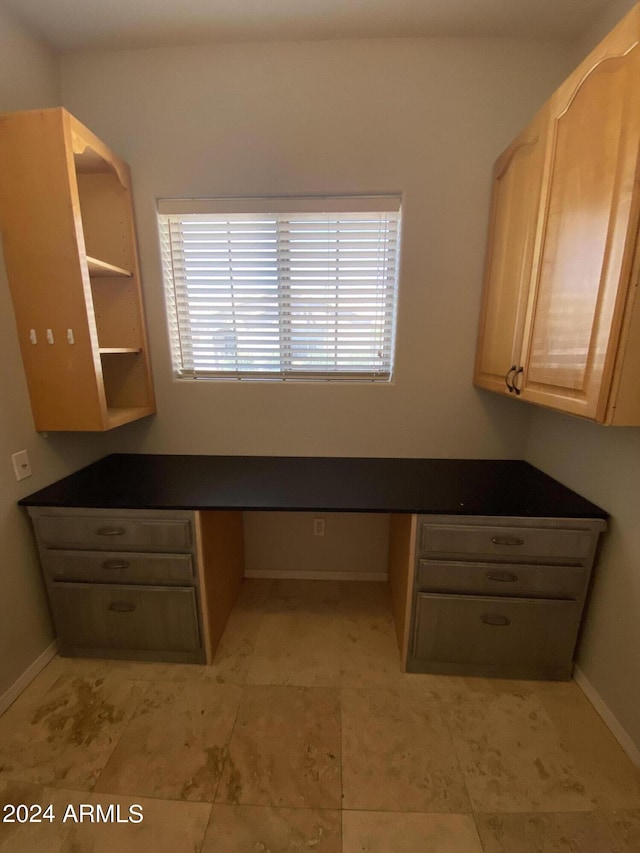 unfurnished office featuring baseboards and built in desk