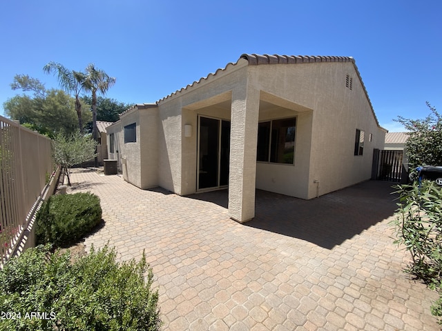 back of house featuring stucco siding, a patio, central AC, and a fenced backyard