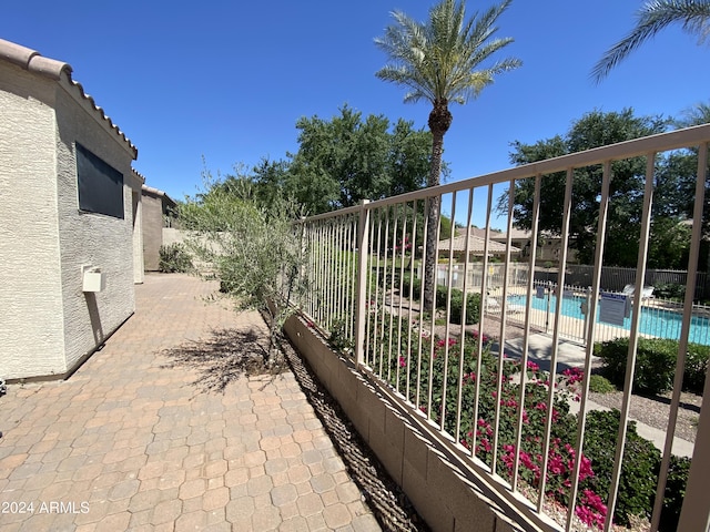 view of patio with a community pool and fence