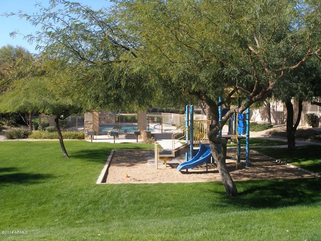 community play area featuring a community pool, a lawn, and fence