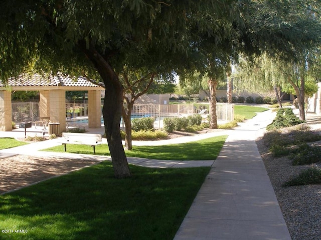 surrounding community featuring a swimming pool, a yard, and fence