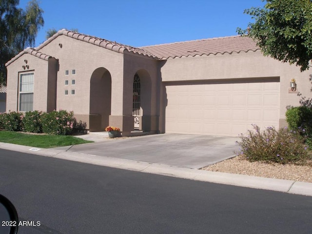 mediterranean / spanish house featuring stucco siding, a garage, driveway, and a tile roof