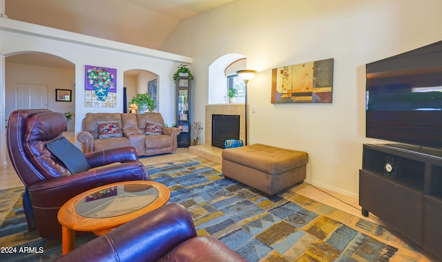 living room with lofted ceiling, a tiled fireplace, and tile patterned flooring