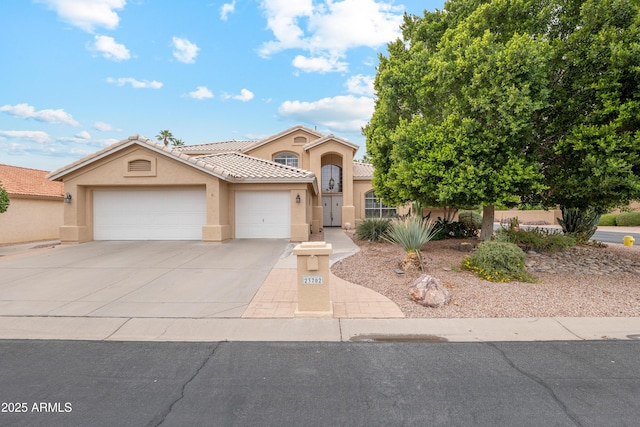 view of front of house featuring stucco siding, driveway, an attached garage, and a tiled roof