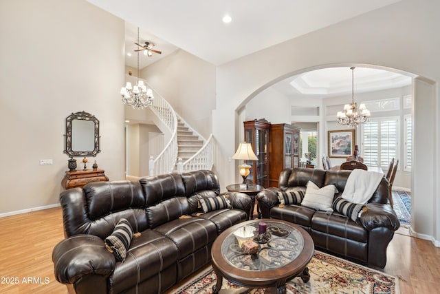 living room featuring light wood-type flooring, baseboards, a chandelier, and stairway