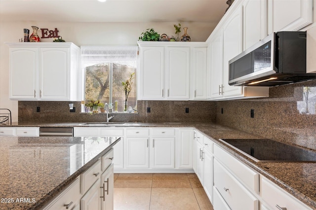 12943 W Mclellan Rd, Glendale, AZ 85307 - kitchen featuring dark stone countertops, stainless steel microwave, black electric cooktop, a sink, and white cabinetry