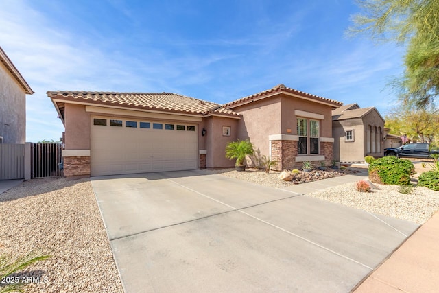 mediterranean / spanish house featuring a tile roof, stucco siding, a garage, stone siding, and driveway