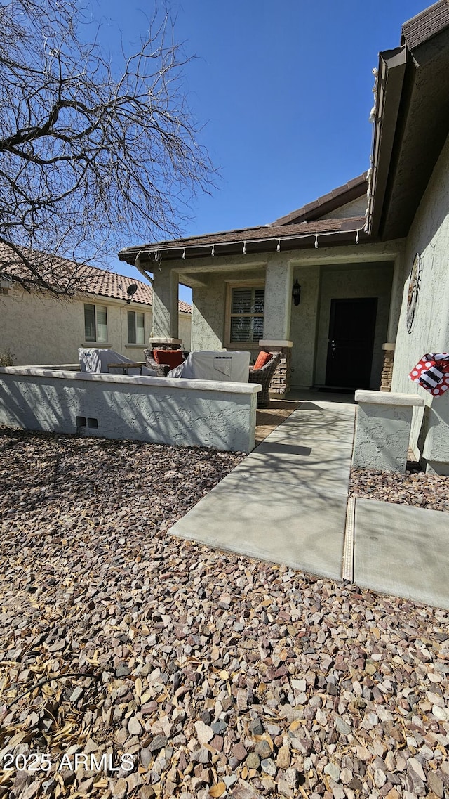 rear view of house with stucco siding and a patio