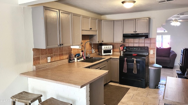 kitchen with sink, kitchen peninsula, a kitchen bar, ceiling fan, and black / electric stove