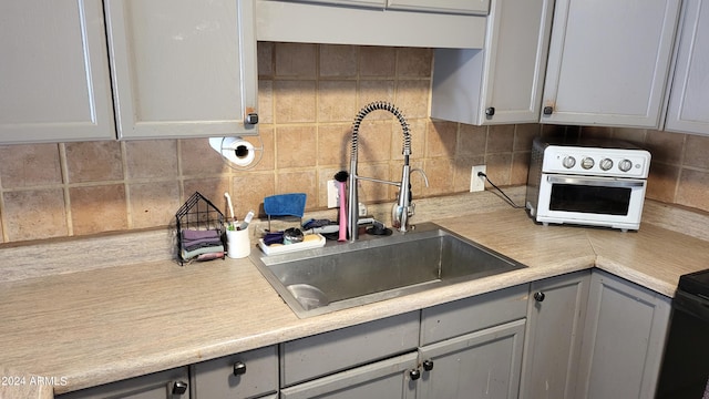 kitchen with decorative backsplash, gray cabinets, and sink