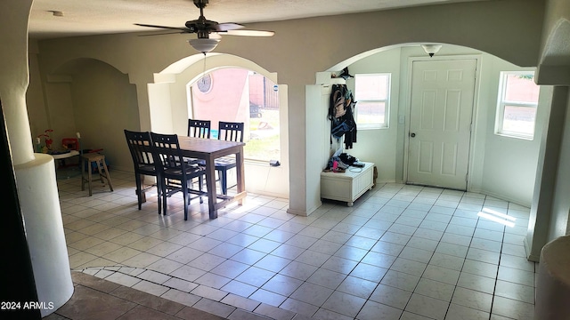 dining room featuring light tile patterned floors, a healthy amount of sunlight, and arched walkways