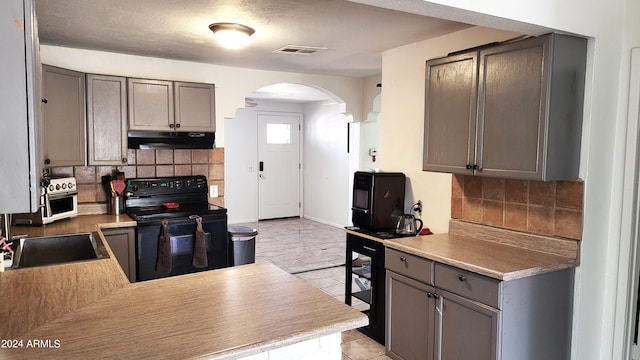 kitchen with black / electric stove, gray cabinets, and backsplash