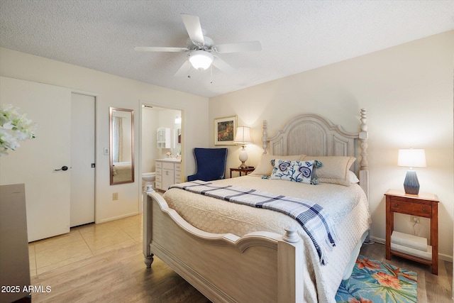 bedroom featuring connected bathroom, a textured ceiling, a ceiling fan, and light wood finished floors