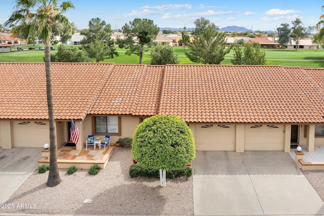 exterior space with a tile roof, concrete driveway, an attached garage, and brick siding