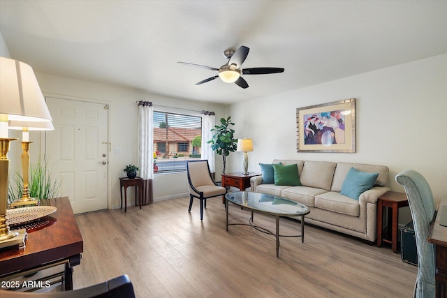 living room featuring baseboards, light wood-style floors, and ceiling fan