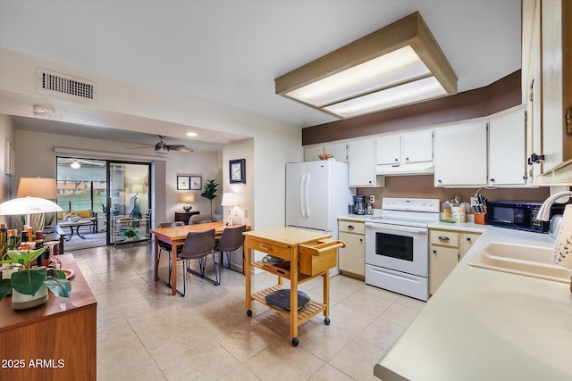 kitchen featuring visible vents, a sink, under cabinet range hood, white appliances, and light countertops