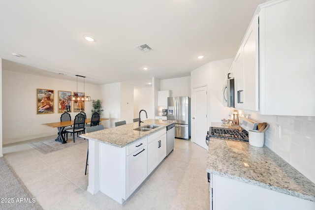 4911 N 193rd Ave, Litchfield Park, AZ 85340 - kitchen featuring stainless steel appliances, a sink, a center island with sink, backsplash, and white cabinets