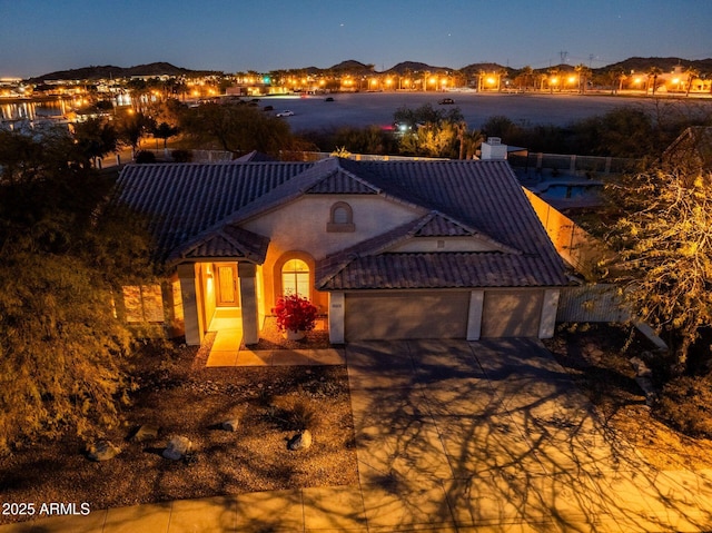 view of front of home featuring an attached garage, driveway, a tile roof, and stucco siding