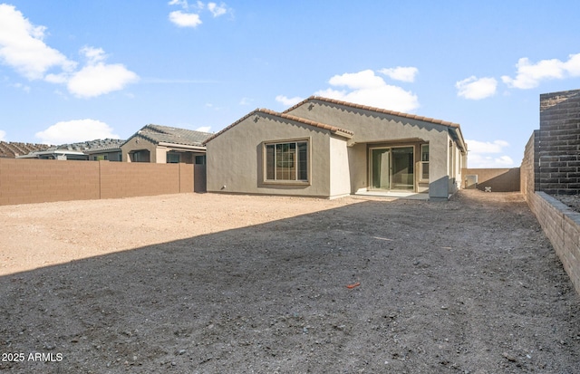 back of property with a tiled roof, a fenced backyard, and stucco siding
