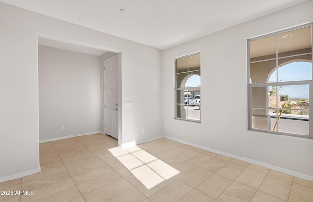 unfurnished room with baseboards and tile patterned flooring
