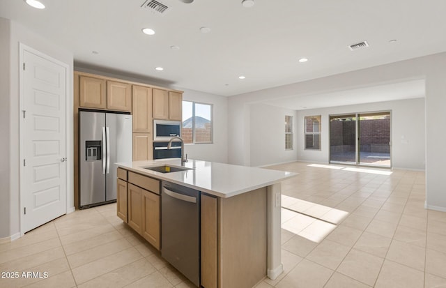 kitchen with appliances with stainless steel finishes, a sink, open floor plan, light tile patterned floors, and visible vents
