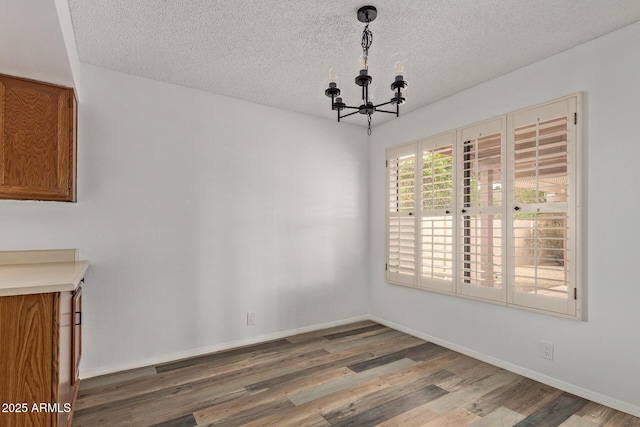 9845 W Behrend Dr, Peoria, AZ 85382 - unfurnished dining area with a notable chandelier, a textured ceiling, baseboards, and wood finished floors