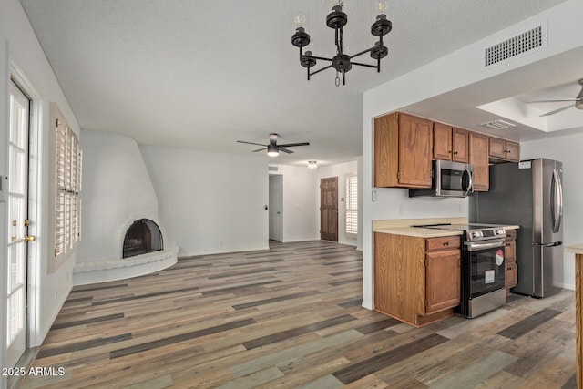 9845 W Behrend Dr, Peoria, AZ 85382 - kitchen featuring ceiling fan with notable chandelier, visible vents, brown cabinetry, and stainless steel appliances