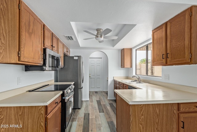 9845 W Behrend Dr, Peoria, AZ 85382 - kitchen with black electric range oven, a sink, brown cabinetry, and a raised ceiling