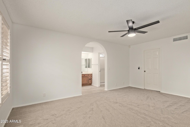 9845 W Behrend Dr, Peoria, AZ 85382 - spare room with a textured ceiling, arched walkways, visible vents, light carpet, and ceiling fan
