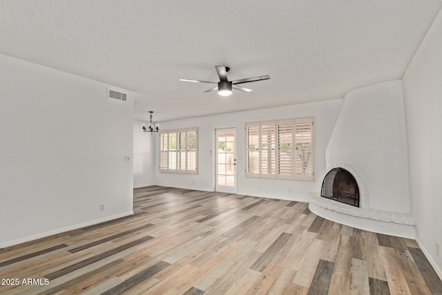 9845 W Behrend Dr, Peoria, AZ 85382 - unfurnished living room with a textured ceiling, visible vents, a fireplace, wood finished floors, and ceiling fan with notable chandelier