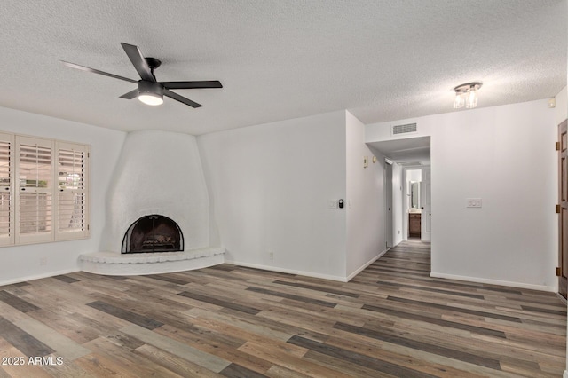 9845 W Behrend Dr, Peoria, AZ 85382 - unfurnished living room with visible vents, baseboards, a fireplace, wood finished floors, and a ceiling fan