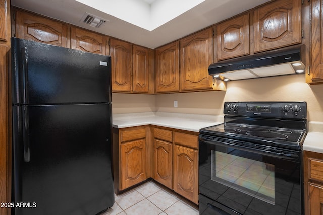 kitchen featuring under cabinet range hood, visible vents, black appliances, and brown cabinetry