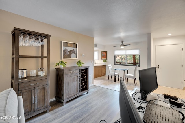 home office featuring visible vents, baseboards, light wood-type flooring, and a ceiling fan