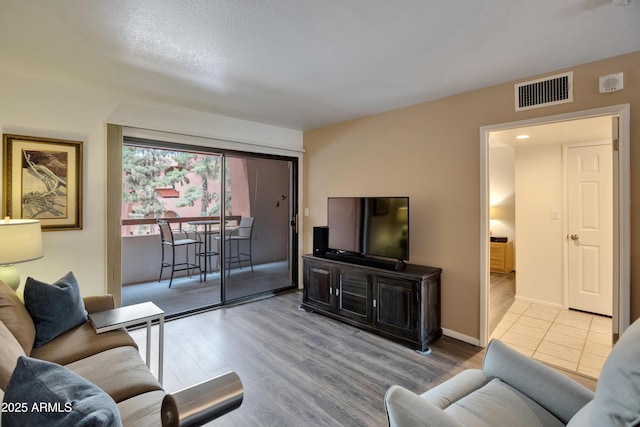 living room with visible vents, baseboards, and wood finished floors