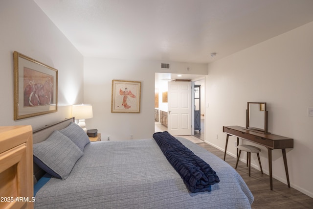 bedroom with visible vents, wood finished floors, and baseboards