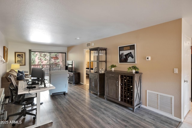 office area featuring a textured ceiling, dark wood-style floors, visible vents, and baseboards