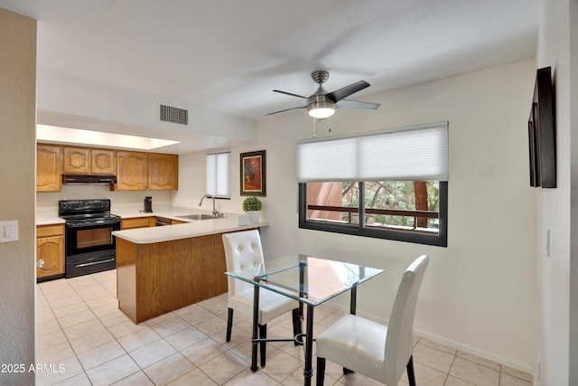 kitchen featuring visible vents, under cabinet range hood, a peninsula, electric range, and a sink