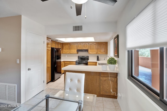 kitchen featuring under cabinet range hood, visible vents, black appliances, and a sink