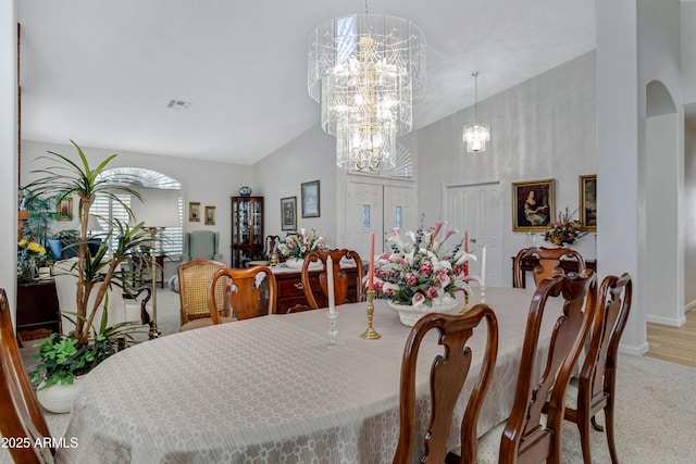 dining area with a notable chandelier, light colored carpet, and lofted ceiling