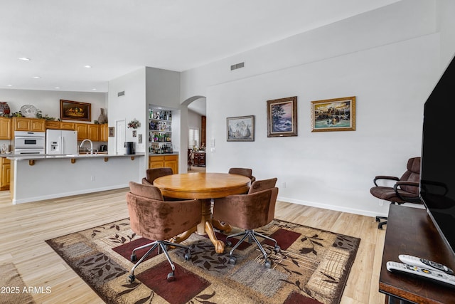 dining room with built in features, light hardwood / wood-style flooring, and sink