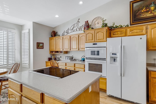 kitchen with a center island, white appliances, and light hardwood / wood-style flooring