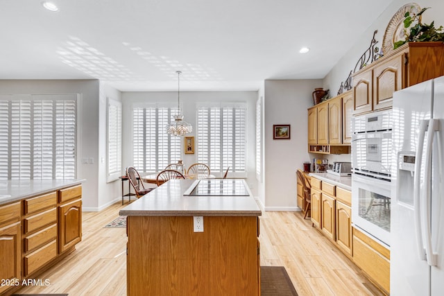 kitchen with pendant lighting, a center island, white appliances, and light hardwood / wood-style floors