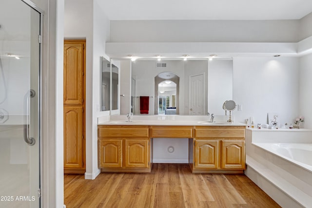 bathroom with plus walk in shower, vanity, and hardwood / wood-style flooring