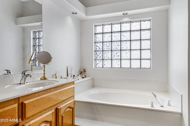 bathroom featuring plenty of natural light, a tub to relax in, and vanity